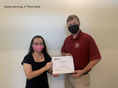 Two people wearing masks holding an award