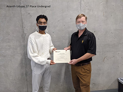 Two people wearing masks holding an award